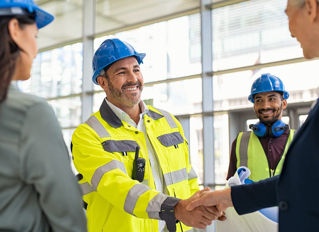 Contact - Portrait of a Cheerful Mature Contractor Shaking Hands with a Businessman During a Meeting at a Commercial Construction Jobsite